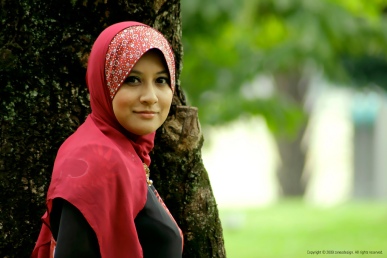 Muslim woman wearing a red hijab, a scarf the covers a woman’s hair and neck.